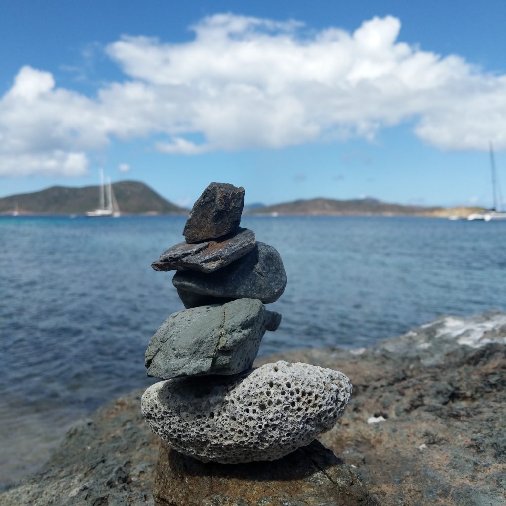 A rock piling with a view of the ocean and boats behind